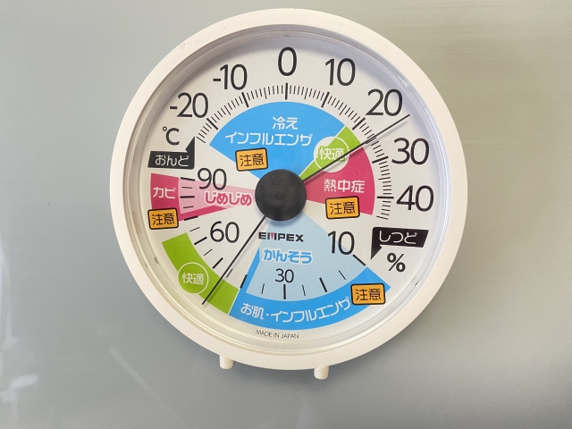 Round white circular gauge with color-coded sections and Japanese warning labels, central knob, brand EMPEX, MADE IN JAPAN; measures environmental risk zones.